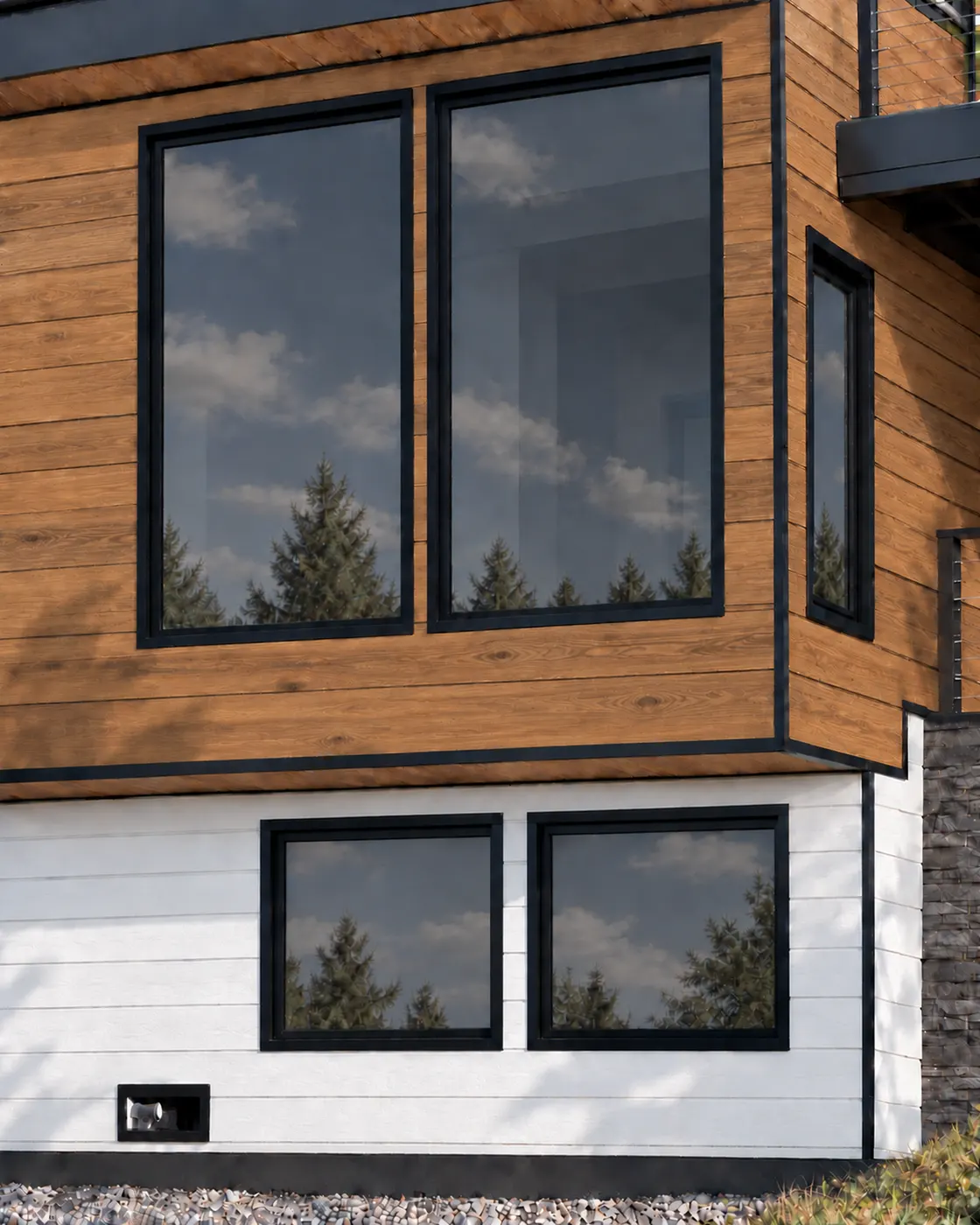Large black-framed windows in wood-look siding above light siding, reflecting the sky and evergreen trees. Panda windows and Edco metal hickory and glacier white metal siding.